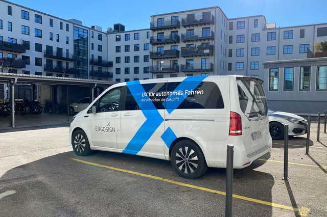 Ein weißer Mercedes Mini-Van mit dem blauen Ergosign Logo, der auf einem Parkplatz steht. parked in a courtyard.
