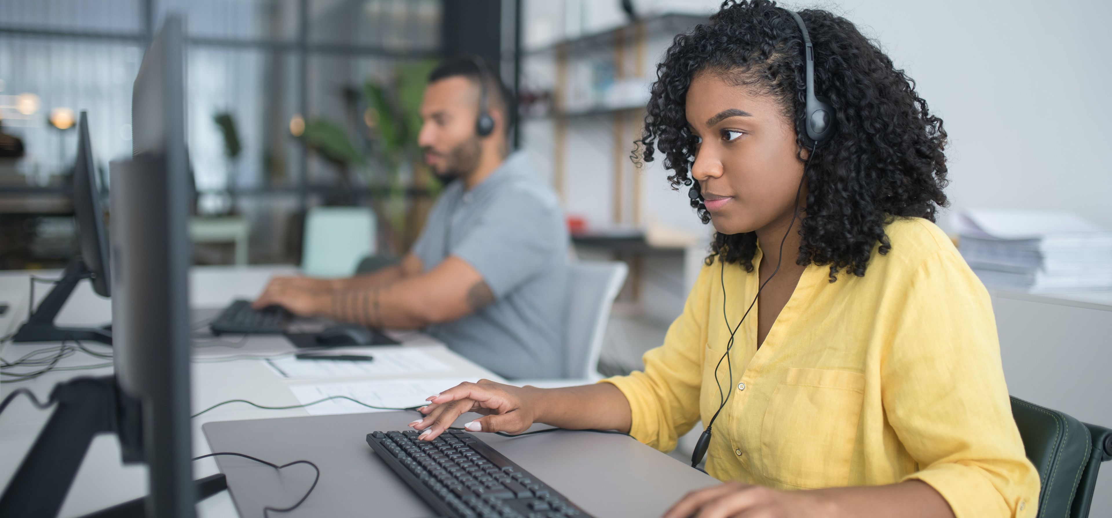 Eine Frau mit Kopfhörern arbeitet konzentriert am Computer.