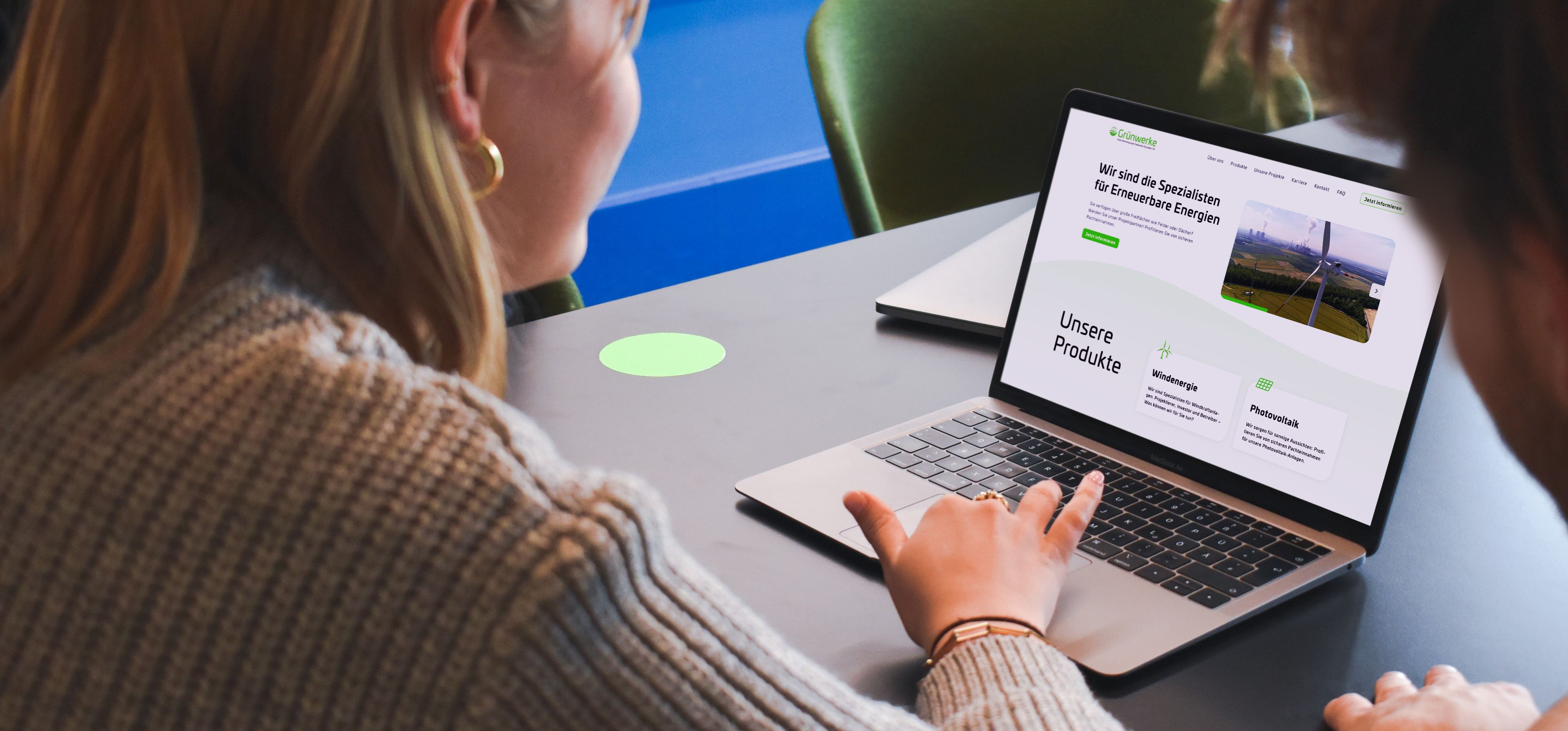 Eine Frau sitzt an ihrem Laptop auf dem die Website der Grünwerke geöffnet ist. Rechts neben ihr sitzt ein Mann, der ebenfalls auf den Bildschirm schaut.