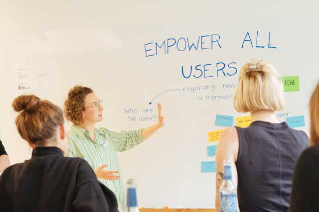 Eine Frau präsentiert ein Whiteboard vor einer Gruppe von Frauen