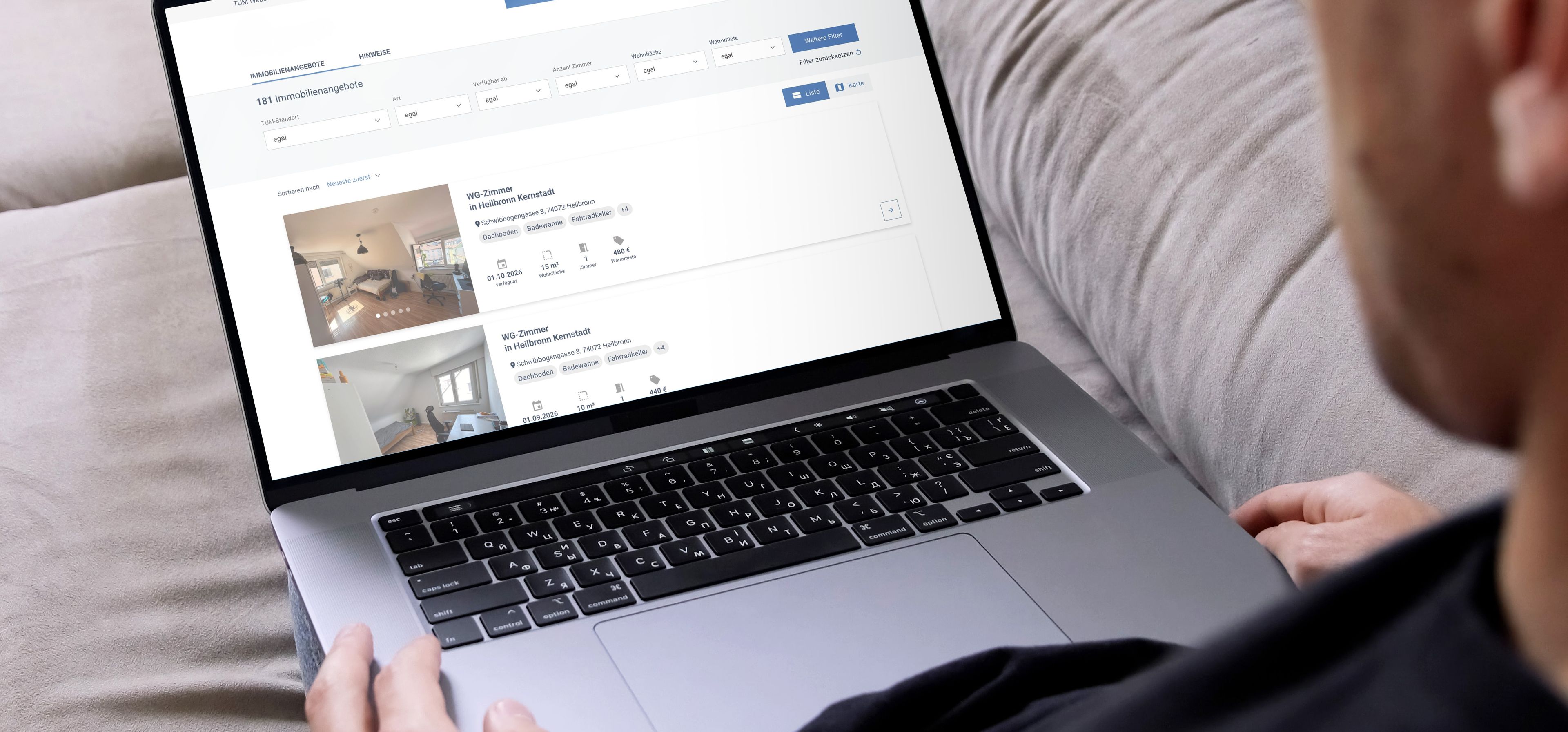 Person auf Sofa durchsucht mit Laptop Immobilienangebote auf einer Webseite. Bildschirm zeigt Wohnungen mit Details und Fotos.