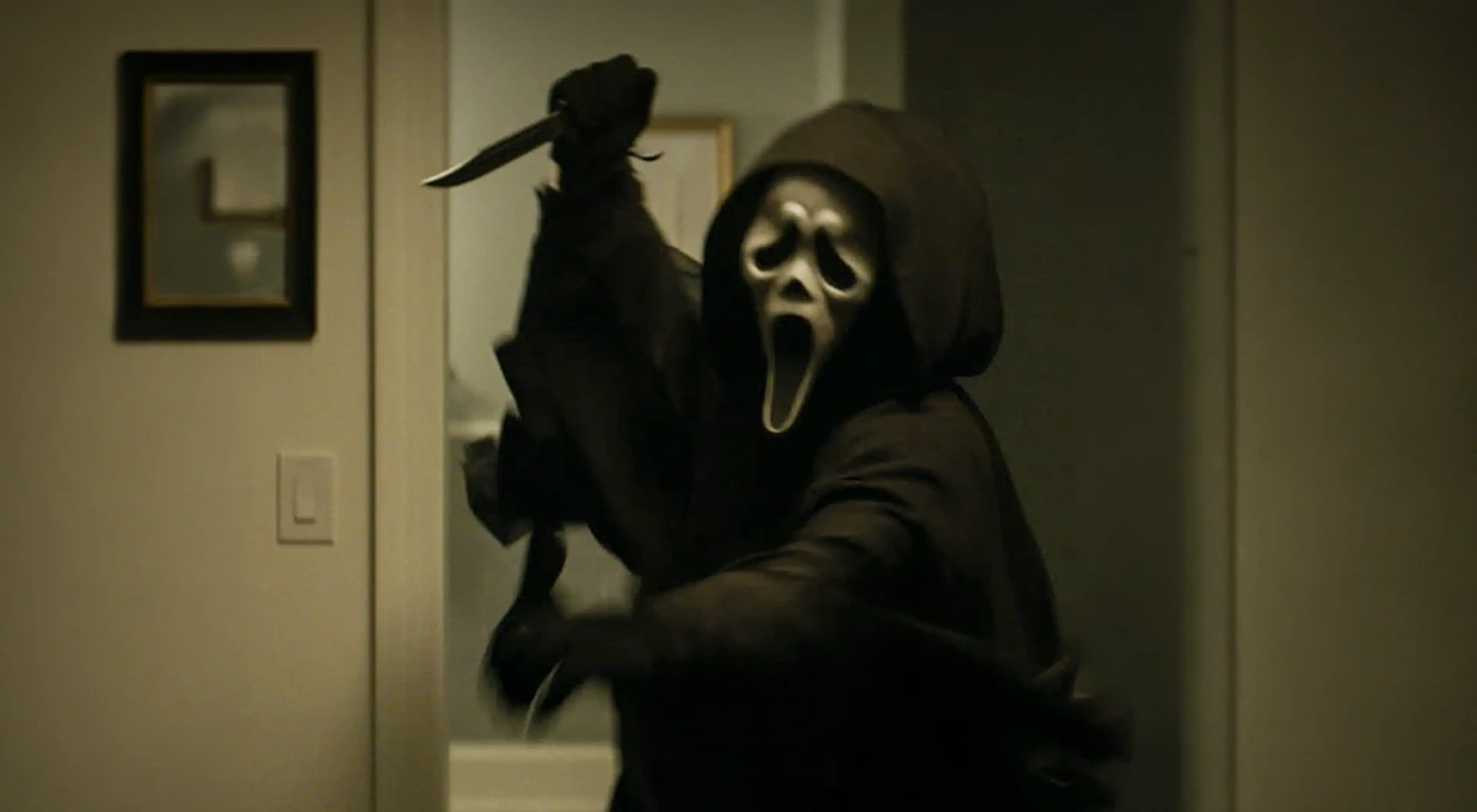 Ghostface masked figure in a dark hoodie holding a knife in a dimly lit hallway, symbolizing fear and anxiety