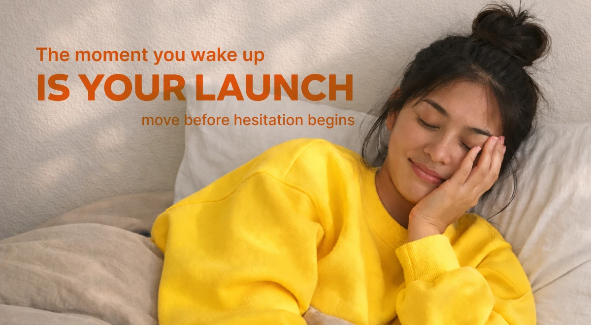 Woman in yellow sweatshirt lying in bed with eyes closed and hand on cheek, embodying a calm morning routine moment and well being mindset