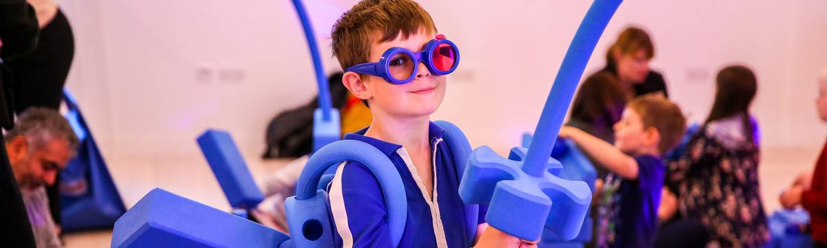 A child wearing blue glasses with foam toys.