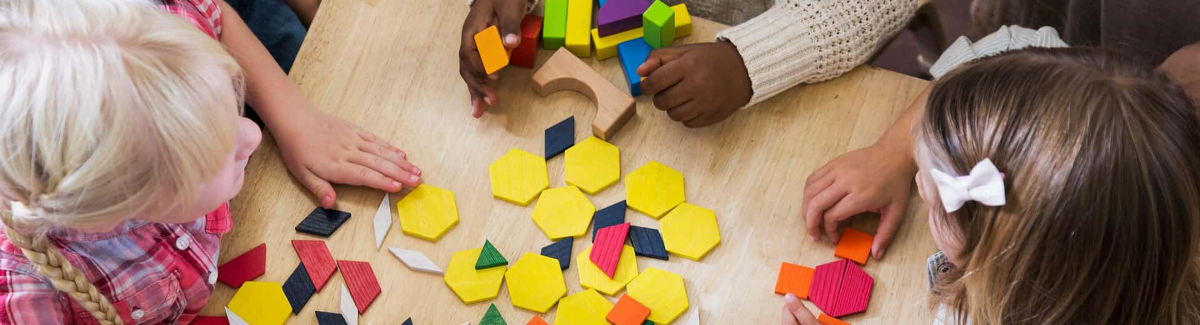 Young children play with brightly colored shapes on a table