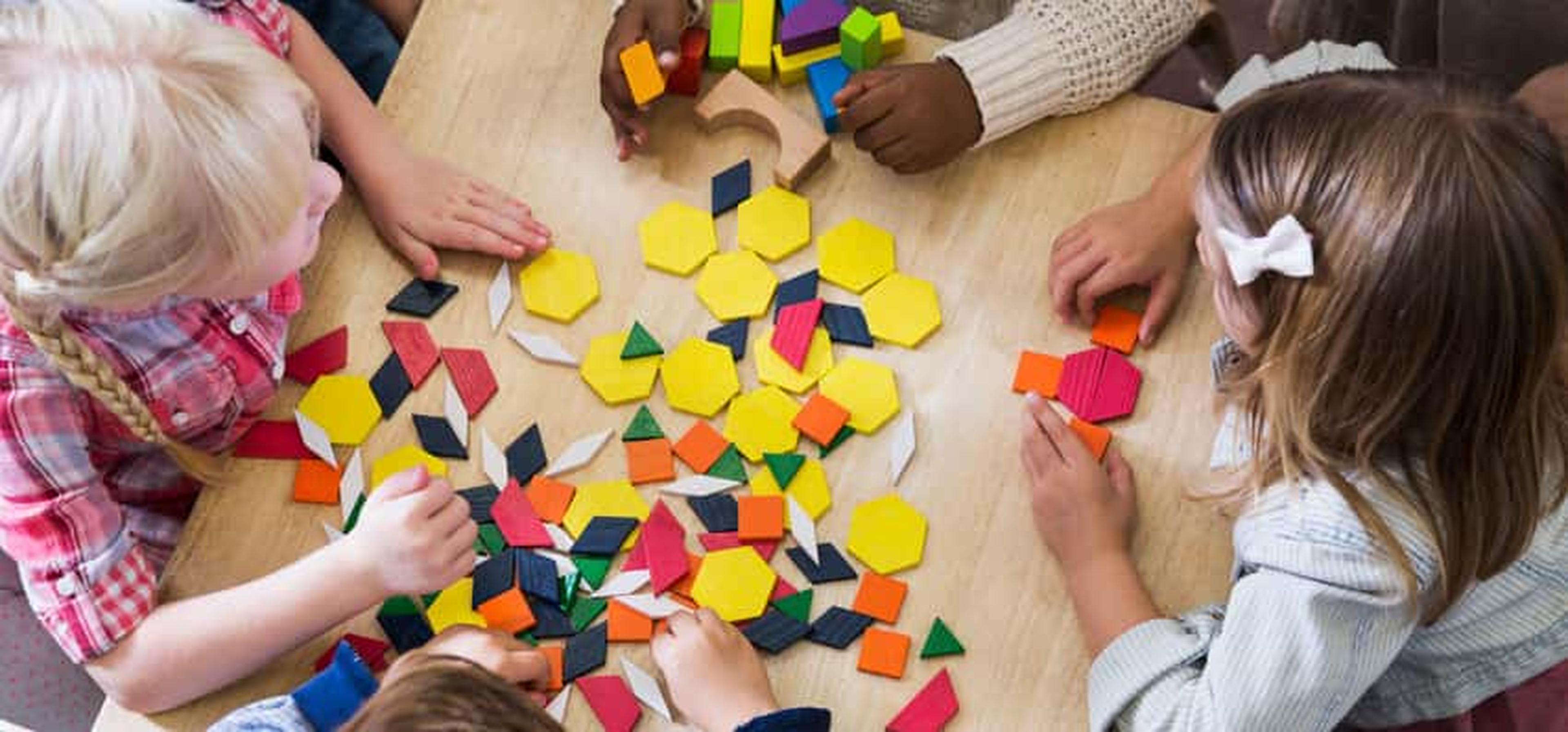 Young children play with brightly colored shapes on a table