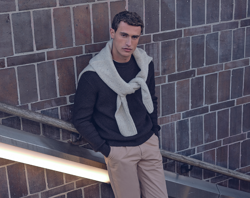 Man gekleed in donkerblauwe trui en beige broek