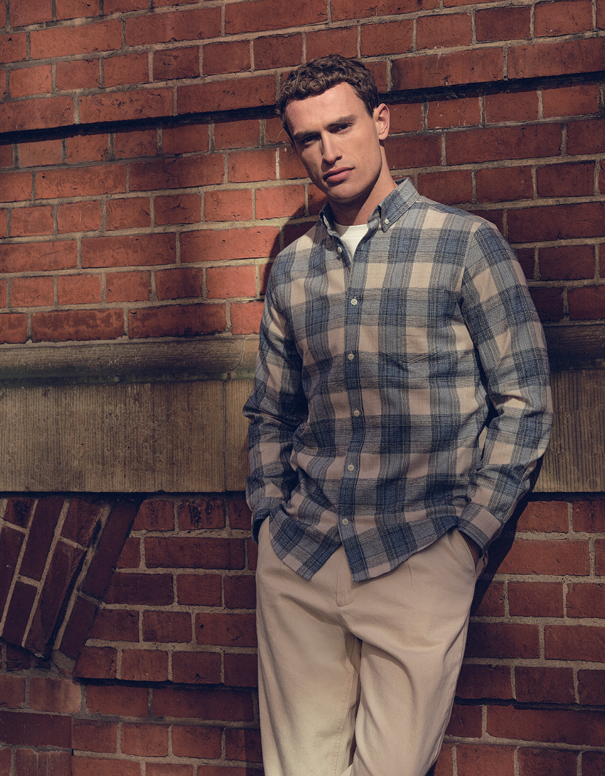 Man gekleed in een geruite overhemd en een beige broek