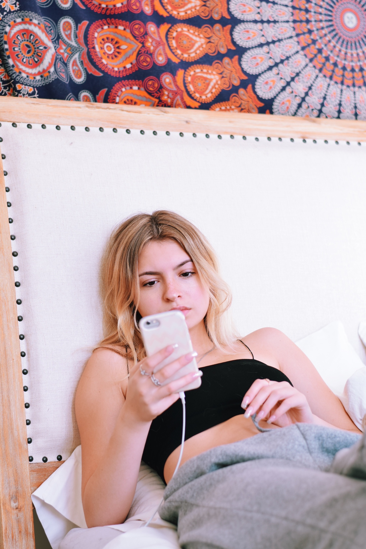 Person sitzt nachdenklich mit Smartphone in einer Toilettenkabine