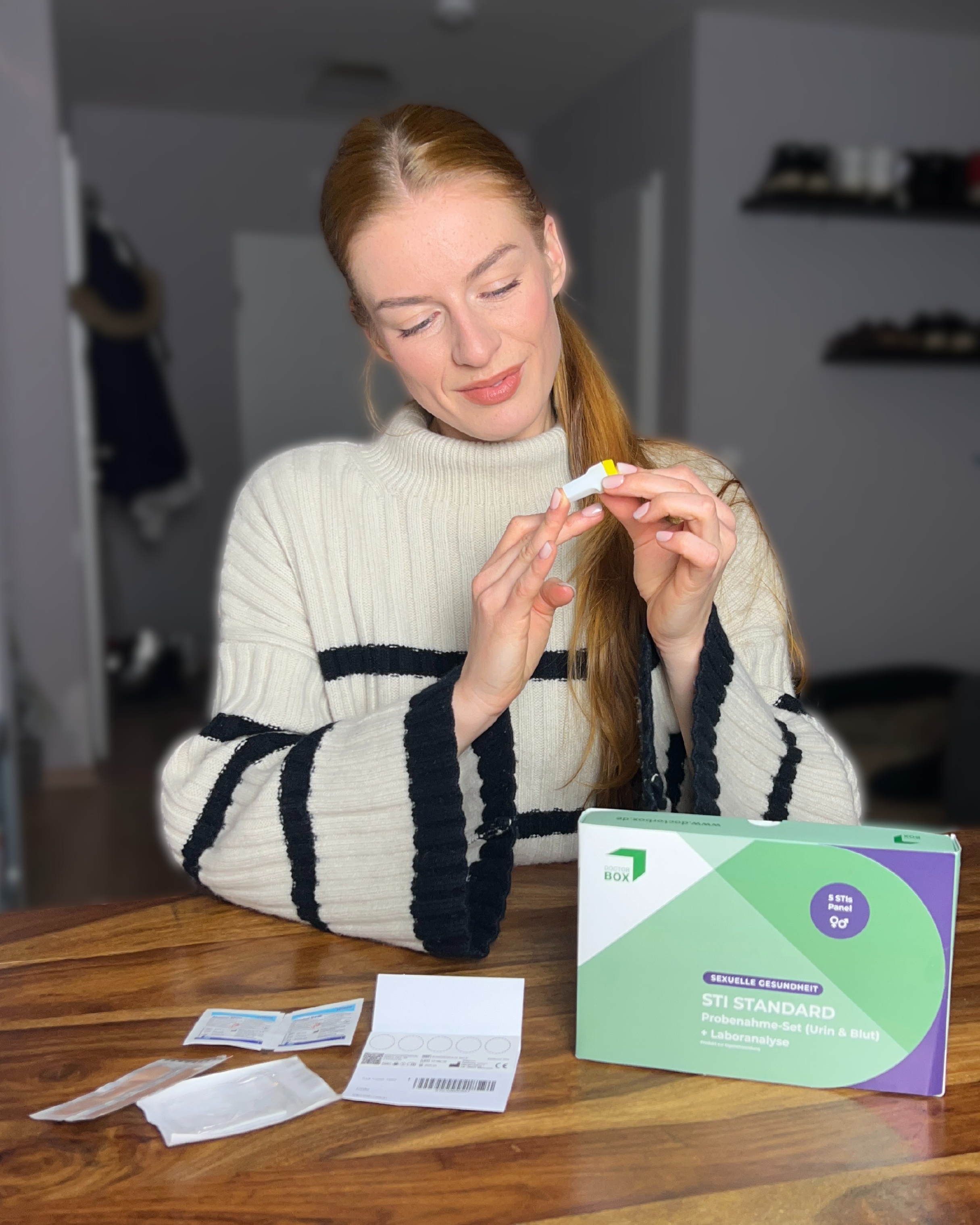 Junge Frau führt einen STI STANDARD Heimtest von DoctorBox durch – mit Urin- und Blutanalyse-Set am Tisch