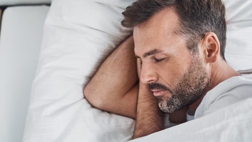Mann liegt im Bett und schläft.