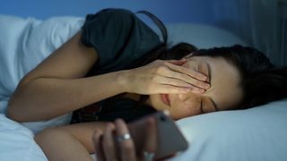 Frau liegt wach im Bett.