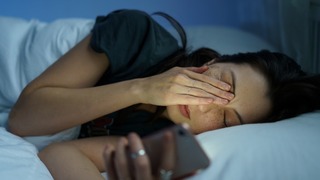 Frau liegt wach im Bett.