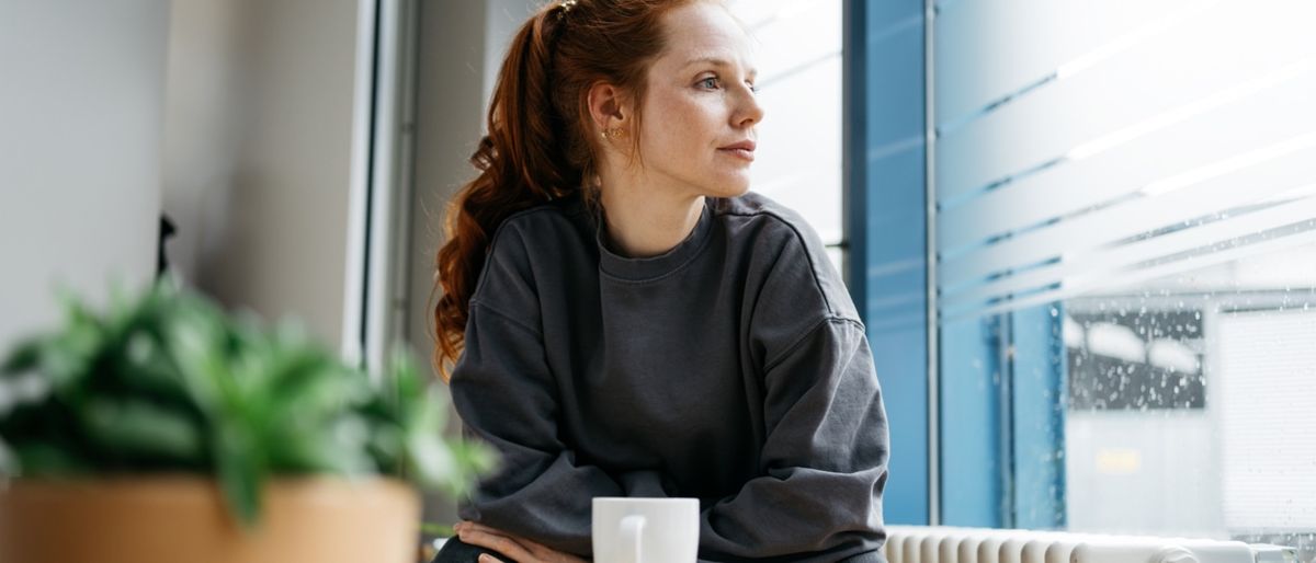 Frau sitzt nachdenklich am Tisch. 