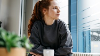 Frau sitzt nachdenklich am Tisch. 