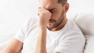 Mann erschöpft und müde im Bett.