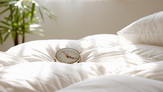 Wecker, der auf Bettdecke liegt.