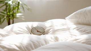 Wecker, der auf Bettdecke liegt.