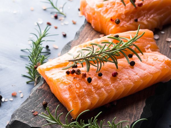 Lachs auf Holzbrett garniert mit Pfeffer und Rosmarinzweig