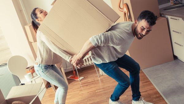 Junges Paar trägt sehr großen Umzugskarton