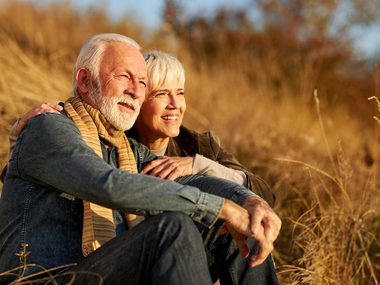 Älteres Paar sitzt entspannt in der Natur im warmen Abendlicht –Lebensqualität bei rheumatischen Beschwerden.