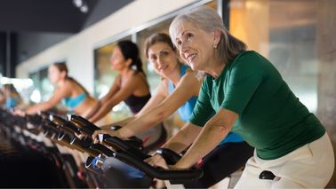 Frauen sitzen auf Ergometern.