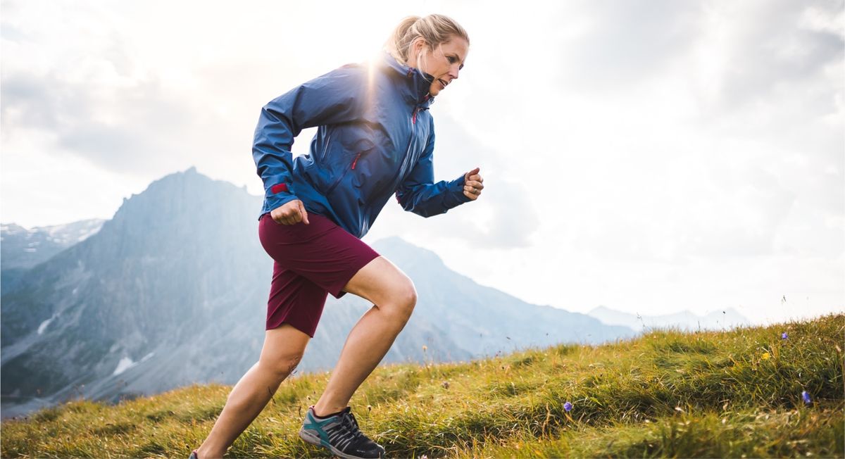 Frau joggt einen Berg hoch.