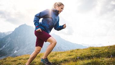 Frau joggt einen Berg hoch.