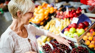 Frau kauft auf Markt frisches Obst und Gemüse ein.