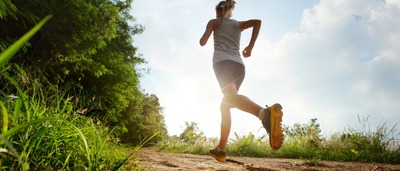 Frau läuft auf einem Feldweg.