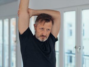 Mann dehnt sich im Stehen – ruhige Alltagsbewegung bei Rheuma.