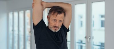 Mann dehnt sich im Stehen – ruhige Alltagsbewegung bei Rheuma.