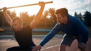 Trainer korrigiert Überkopf-Kniebeuge