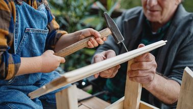 Großvater und Enkel bauen ein Vogelhaus.