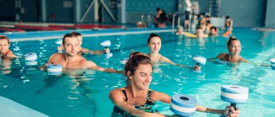 Sportgruppe beim gelenkschonenden Wassergymnastik-Training mit Aqua-Hanteln