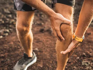 Symbolbild: Mann hält beim Laufen sein schmerzendes Knie – Hinweis auf Rheuma und Gelenkschmerzen.