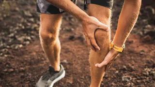 Symbolbild: Mann hält beim Laufen sein schmerzendes Knie – Hinweis auf Rheuma und Gelenkschmerzen.