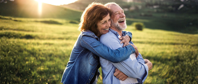 Paar spaziert lachend auf einer Wiese – Symbol für Bewegung in der Natur und Entlastung bei Hämorrhoiden-Beschwerden.