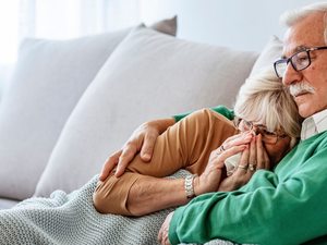 Älteres Paar auf dem Sofa – Frau erkältet mit Taschentuch