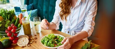 Frau isst eine grüne Salatschüssel mit Gemüse und Nüssen –Mahlzeit im Essensfenster beim Intervallfasten.