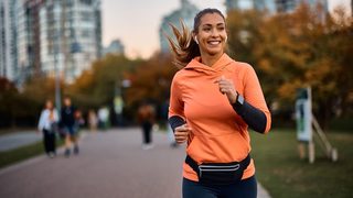 Frau joggt entspannt im Stadtpark – moderates Lauftraining unterstützt die natürliche Sehnen Regeneration.