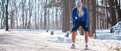 Junger Mann bei einer kurzen Pause vom Lauftraining im Winter
