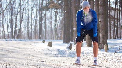 Junger Mann bei einer kurzen Pause vom Lauftraining im Winter