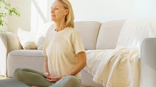 Frau sitzt entspannt auf einer Yogamatte und übt Atemfokus - Achtsamkeitshack zur Unterstützung bei Schwindel im Alltag.