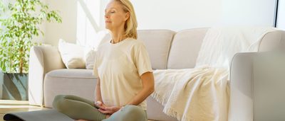 Frau sitzt entspannt auf einer Yogamatte und übt Atemfokus - Achtsamkeitshack zur Unterstützung bei Schwindel im Alltag.