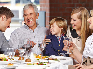 Mehrgenerationen-Familie beim Essen mit Wasser und Salat; Symbol für ausgewogene Ernährung, Leber entgiften und Darmgesundheit.