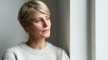Frau wirkt nachdenklich und zeigt Anzeichen eines psychisch bedingten beklemmenden Gefühls