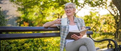 Ältere Frau liest im Garten – Informationen zur Blasenentleerungsstörung im Alter
