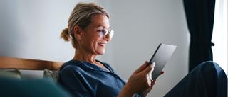 Person sitzt entspannt im Schlafzimmer und bedient Smart-Home-Funktionen über ein Tablet