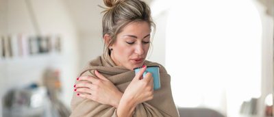 Frau erholt sich zu Hause mit Wärme und Tee – sanfte Hausmittel bei Bronchitis-Symptomen